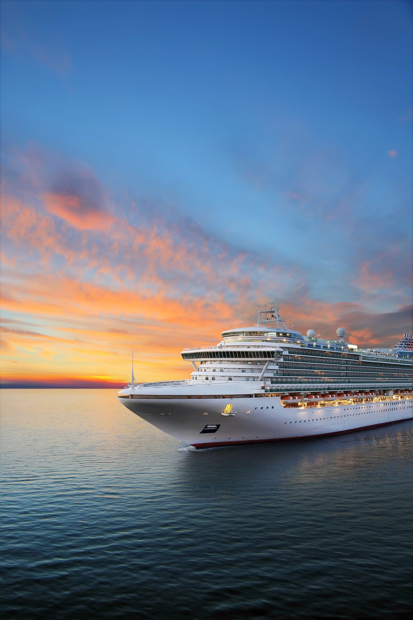a large cruise ship sailing on calm waters during sunset. The sky is vibrant with hues of orange, pink, and blue, reflecting the beauty of the sunset.