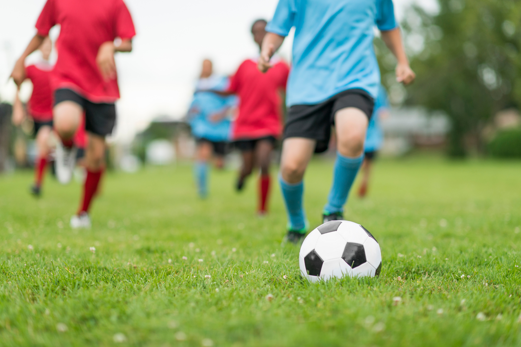 kids running and playing soccer in red and blue uniforms